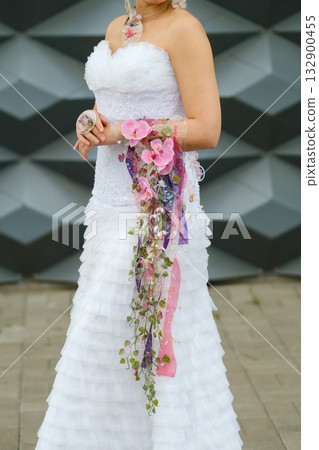 Beautiful bride in white strapless wedding dress with floral details poses for a photo against a modern geometric background in springtime Beautiful bride in white strapless wedding dress with floral details poses for a photo against a modern geometric background in springtime 132900455