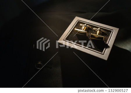 Elegant gold cufflinks displayed in a sleek black box on a tailored shirt with soft lighting highlighting their shine 132900527