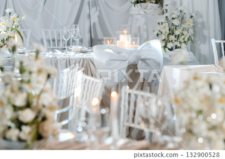 Elegant wedding reception setup with white floral arrangements, soft candlelight, and decorative table settings at a serene venue 132900528