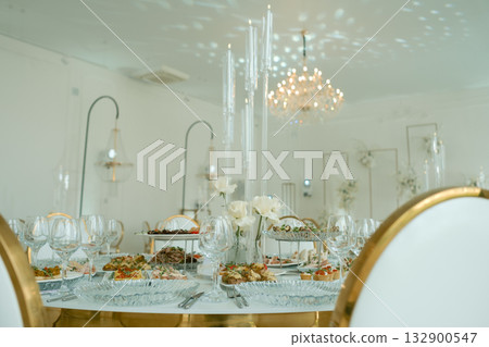 Elegant dining setup with gourmet dishes and floral centerpieces in a modern venue decorated with soft lighting 132900547