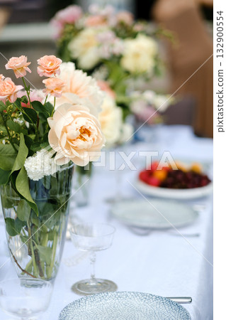 Elegant table setting adorned with fresh flowers and vibrant fruit arranged for a special gathering outdoors during a sunny afternoon 132900554