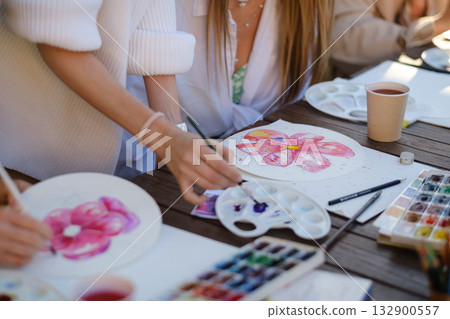 Painting colorful flowers during an outdoor art class in a sunny garden setting with participants engaged in creative activities 132900557