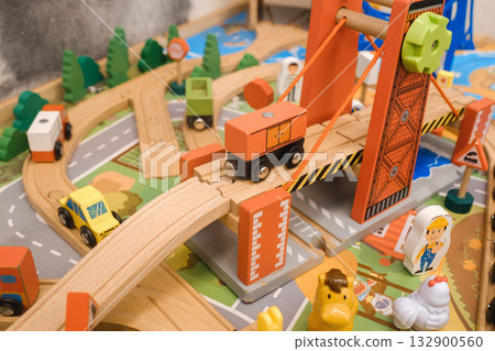 Wooden toy city scene with vehicles crossing a bridge and children playing in a colorful environment filled with tracks and figures Wooden toy city scene with vehicles crossing a bridge and children playing in a colorful environment filled with tracks and figures 132900560
