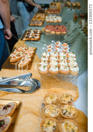 Buffet table filled with a variety of appetizers and snacks at a social gathering in an indoor venue during daytime Buffet table filled with a variety of appetizers and snacks at a social gathering in an indoor venue during daytime 132900573