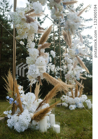 Elegant floral arrangement with white flowers and pampas grass for outdoor wedding setup in serene natural environment during daylight 132900594