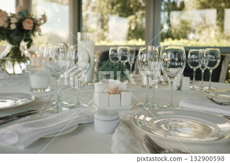 Elegant dining setup with glassware and floral centerpiece at a scenic restaurant during daytime 132900598