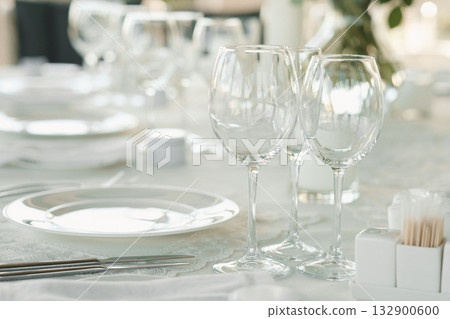 Elegant dining setup with glassware and tableware prepared for a special event at a cozy restaurant during daytime 132900600