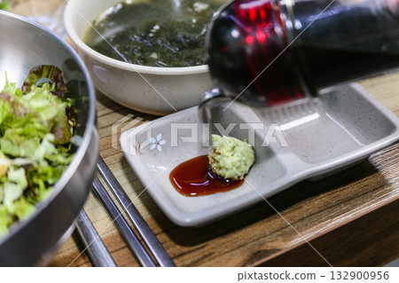 Pour Korean soy sauce into a bowl with wasabi 132900956