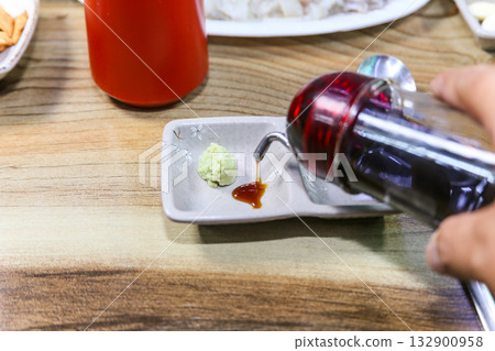 Pour Korean soy sauce into a bowl with wasabi 132900958