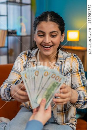 Sudden happiness Indian woman joyfully celebrating receiving plenty cash dollar showing victory sign Sudden happiness Indian woman joyfully celebrating receiving plenty cash dollar showing victory sign 132901782