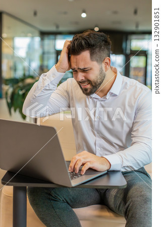 Sad businessman using laptop loses becoming shocked sudden lottery results in modern hotel lobby Sad businessman using laptop loses becoming shocked sudden lottery results in modern hotel lobby 132901851