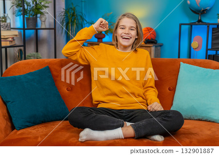 Teenager boy watching TV, celebrating victory, cheering for sports team, sitting on sofa at home 132901887