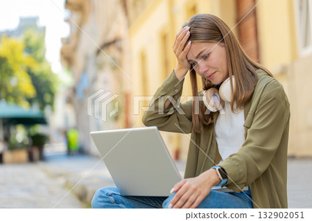 Displeased young woman using laptop working, loses becoming surprised sudden lottery result outdoors Displeased young woman using laptop working, loses becoming surprised sudden lottery result outdoors 132902051