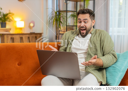 Surprised Caucasian brunette man using laptop computer sitting on sofa couch at home apartment Surprised Caucasian brunette man using laptop computer sitting on sofa couch at home apartment 132902076