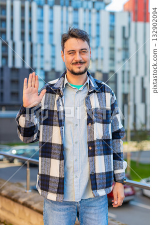 Cheerful mature man tourist smiling at camera, waving hands gesturing hello standing on city street Cheerful mature man tourist smiling at camera, waving hands gesturing hello standing on city street 132902094