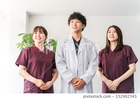 Male and female medical staff including doctors, nurses and doctors wearing white coats and scrubs Male and female medical staff including doctors, nurses and doctors wearing white coats and scrubs 132902343