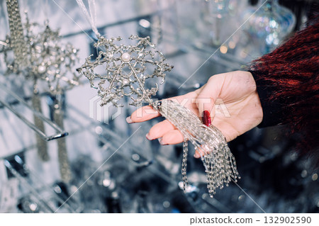 Close-up of a woman's hand holding sparkling beaded holiday garlands among crystal and sequin decorations. Beaded holiday garlands, premium Christmas embellishments, crystal ornament 132902590