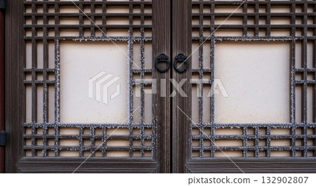 Traditional Korean wooden door with ornate metal grid pattern and circular ring handles featuring geometric lattice design Traditional Korean wooden door with ornate metal grid pattern and circular ring handles featuring geometric lattice design 132902807