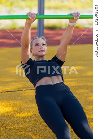 Woman Performing Outdoor Calisthenics Exercise at a Fitness Park 132903204