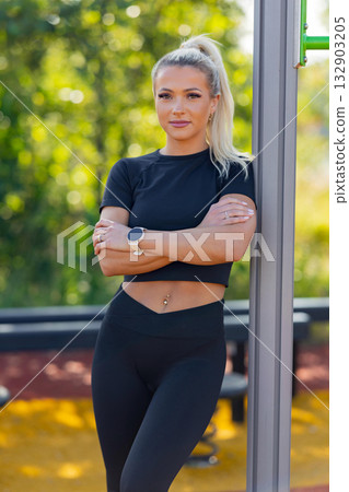 Confident woman standing outdoors at a fitness park with a smartwatch 132903205