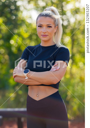 Confident fitness woman outdoors wearing a smartwatch embracing her fitness journey 132903207