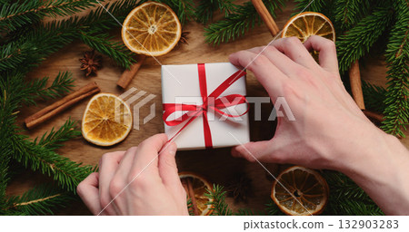 Top view of man hands unwrap christmas gift on decorated table Top view of man hands unwrap christmas gift on decorated table 132903283