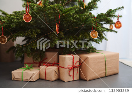 Small christmas tree with gifts in paper wrap near window Small christmas tree with gifts in paper wrap near window 132903289