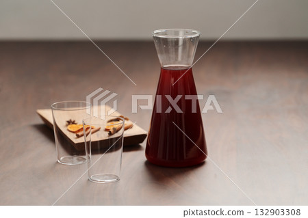 Mulled wine in glass carafe and tumbler glasses on walnut table Mulled wine in glass carafe and tumbler glasses on walnut table 132903308