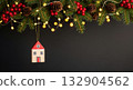 Christmas border of fir branches, cones, and lights with a hanging miniature wooden house ornament on a dark background. 132904562