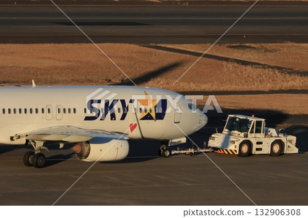Airliner being towed by a towing tractor 132906308