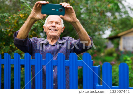 Grandfather takes selfie in front of his country house in village Grandfather takes selfie in front of his country house in village 132907441