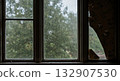 Cracked window with rain in abandoned wooden house during storm with peeling wallpaper and gray light 132907530