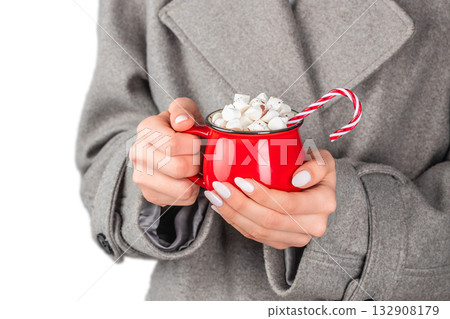 Woman in gray coat holding red mug with hot chocolate, marshmallows, and candy cane, cozy winter holiday concept on white background Woman in gray coat holding red mug with hot chocolate, marshmallows, and candy cane, cozy winter holiday concept on white background 132908179