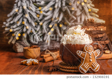 Cup of hot chocolate with whipped cream and gingerbread cookie on wooden table, festive Christmas scene with snowy tree, cinnamon sticks and bokeh lights, cozy winter holiday atmosphere Cup of hot chocolate with whipped cream and gingerbread cookie on wooden table, festive Christmas scene with snowy tree, cinnamon sticks and bokeh lights, cozy winter holiday atmosphere 132908191