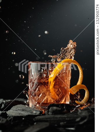 Piece of ice falls into the glass with a cocktail. 132908774