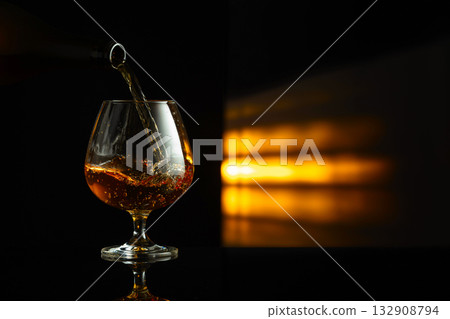 Pouring brandy from a bottle into a snifter. 132908794