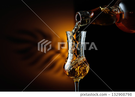 Rum being poured from a bottle into a glass. 132908798