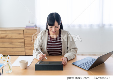 一位年輕女子手持 Apple Pencil 參加遠距課程。 132908872