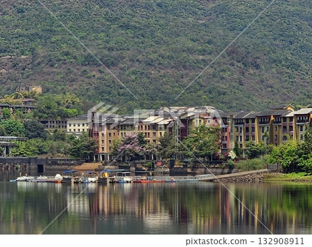 Lakeside architecture Modern lakeside buildings surrounded by hills and lush greenery, showcasing resort lifestyle and scenic living. 132908911