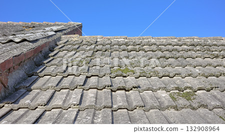 Old building asbestos roof against the blue sky. 132908964