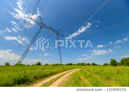 The Power Lines Stand Tall Against a Bright Blue Sky Over a Lush Green Landscape Below The Power Lines Stand Tall Against a Bright Blue Sky Over a Lush Green Landscape Below 132909238
