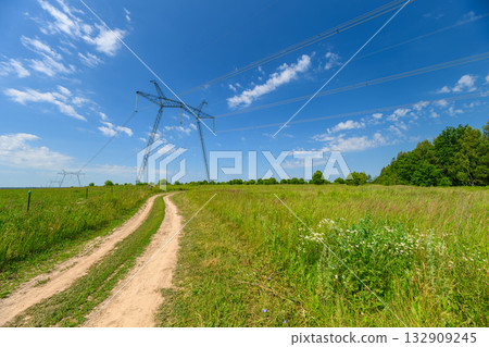 A Tranquil Countryside Path Dancing Under a Blue Sky and Power Lines Stretching Across A Tranquil Countryside Path Dancing Under a Blue Sky and Power Lines Stretching Across 132909245