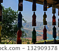 Hanging bottle art Row of colorful recycled plastic bottles hanging as decor with stunning valley and lake view in the background, representing creativity and sustainability. 132909378