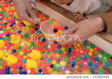 Parent and child hands scooping up super balls at a festival 132909484