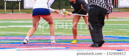 Faceoff in Intense Girls Lacrosse Game on Colorful Field Faceoff in Intense Girls Lacrosse Game on Colorful Field 132909917