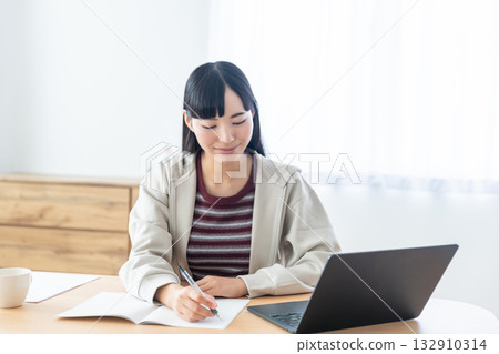一位年輕女子在遠距課堂上做筆記 一位年輕女子在遠距課堂上做筆記 132910314