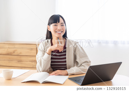 A young woman taking notes during a remote class 132910315