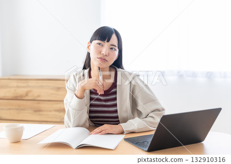 A young woman taking notes during a remote class 132910316