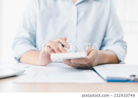 Concept of tax filing and accounting. Businesswoman works with calculator and financial documents on office desk, analyzing income tax report, budget management and financial planning with accuracy. Concept of tax filing and accounting. Businesswoman works with calculator and financial documents on office desk, analyzing income tax report, budget management and financial planning with accuracy. 132910749