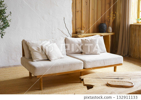 Modern minimalist interior of living room with beige sofa, rustic wooden table in natural light Modern minimalist interior of living room with beige sofa, rustic wooden table in natural light 132911133